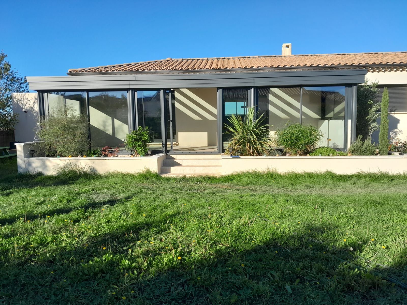Véranda Bioclimatique : Innovation et Confort par une Entreprise de Rénovation à Nîmes Cette véranda bioclimatique, conçue par une entreprise de rénovation à Nîmes, offre une solution innovante pour profiter de votre espace extérieur en toute saison. Avec ses grandes ouvertures, elle permet une régulation naturelle de la température, assurant confort et économie d'énergie. Que vous ayez besoin de services de carreleur extérieur, de pose de parquet flottant, ou d'enduit de façade, notre expertise couvre tous vos projets de second œuvre. Faites également appel à nos compétences pour la construction de clôtures gabion, les travaux sur murs porteurs, et les finitions de peintre intérieur.