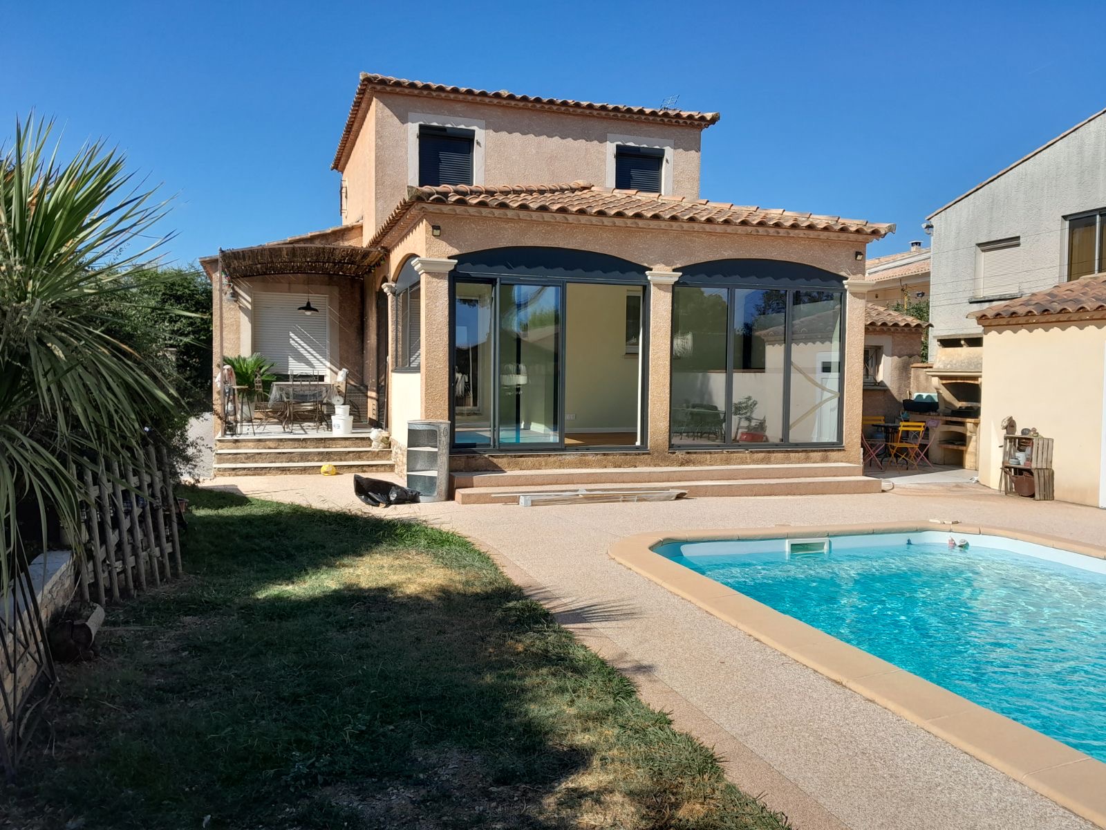 Véranda Éclatante sur Piscine : Confort et Élégance par une Entreprise de Rénovation à Nîmes Cette magnifique véranda extérieure, conçue par une entreprise de rénovation à Nîmes, transforme votre espace de vie en une oasis de confort et d'élégance. Profitez d'un cadre idéal pour vos moments de détente tout en bénéficiant de la pose de parquet flottant, des services d'un carreleur extérieur, et des finitions soignées d'un peintre intérieur. Notre expertise couvre également l'enduit de façade, la construction de clôtures gabion, et les travaux sur murs porteurs. Pour tous vos projets de second œuvre, faites confiance à notre savoir-faire.
